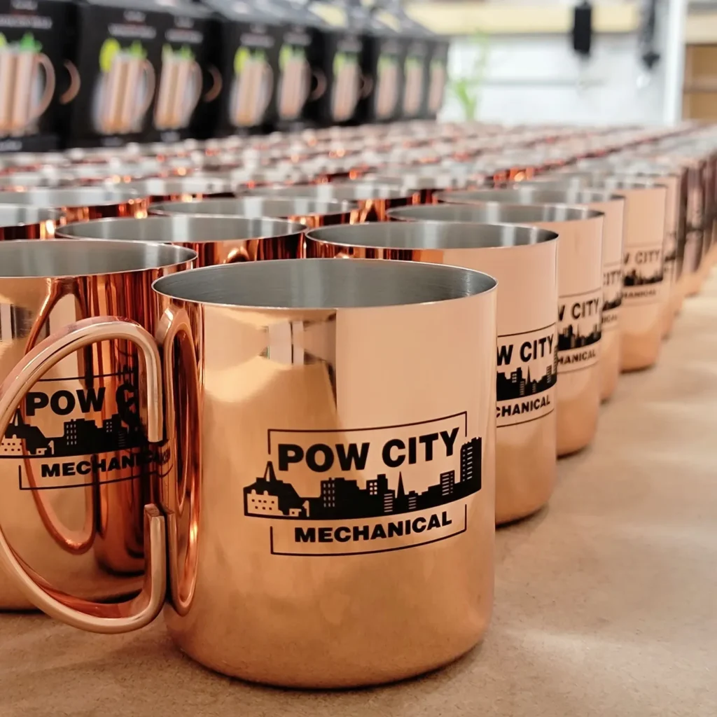 A photo of a large amount of custom engraved copper mugs